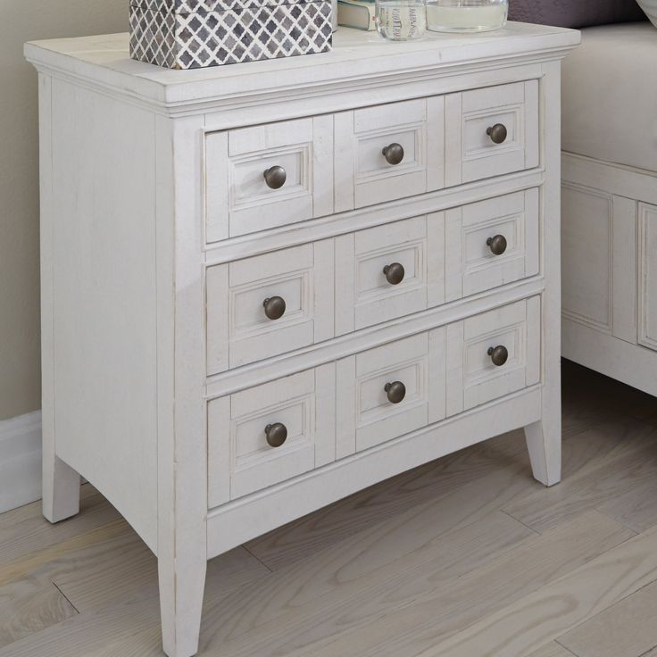 A White Dresser Sitting Next To A Bed With Pillows On It's Headboard pertaining to The Art of Reflection How the Magnussen Heron Cove Mirror Transforms Spaces